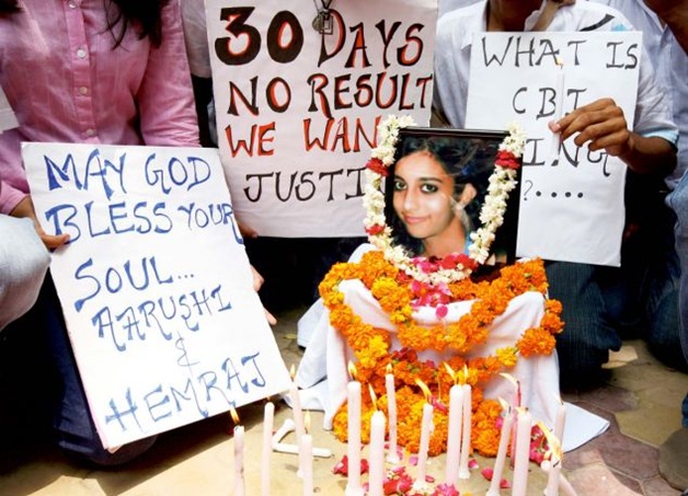 Friends and supporters gather with placards and lighted candles around a picture of Aarushi Talwar during a rally in New Dehi