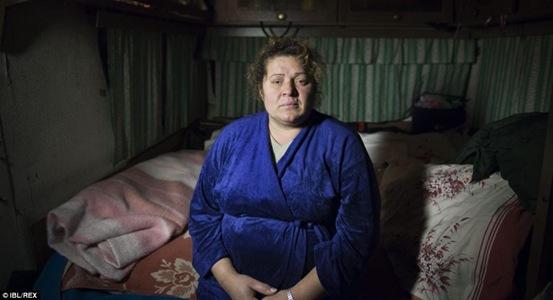 Viorica Vaduva, pictured sitting in the bedroom of her temporary home, is the sole provider for her family back in Romania