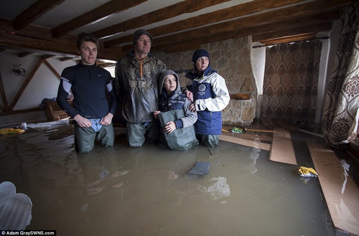 Mark and Kate Kirby with sons Dom, 16, left, and Theo, 10, in their devastated home in Moorland, Somerset