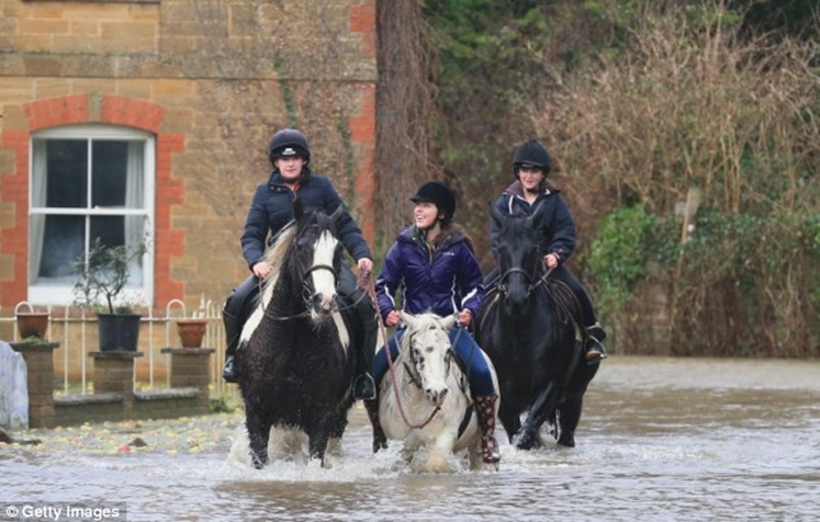 People ride horses through flood water near Langport in Somerset, England during this month's flash-flooding