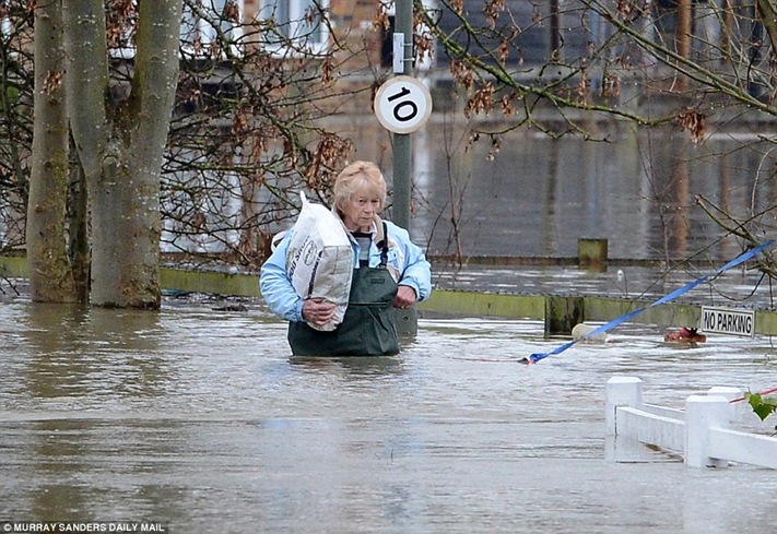 Waist high A local resident makes her way through flood water in Shepperton, Middlesex