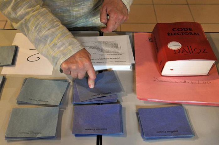 A volunteer counts voting envelopes during the first round of local elections at a polling station