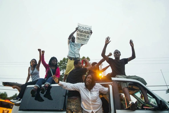 protesters-raise-their-hands-as-they-drive-past-in-a-van-during-a-demonstration-to-protest-the-shooting-of-michael-brown-and-the-resulting-police-response-in-ferguson-missouri-august-15-2014