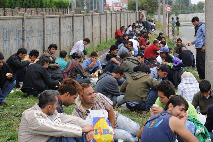 Immigrants eating food by railway sidings in Calais