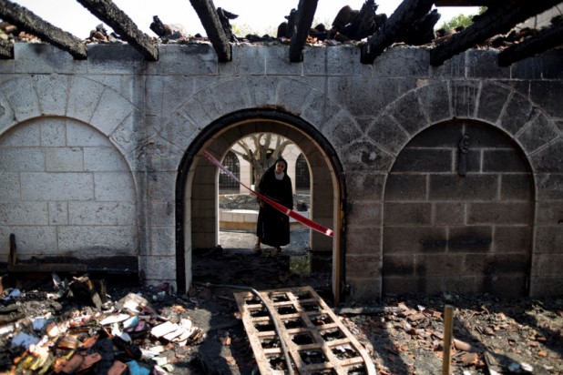 A nun surveys heavy damage at the Church of the Multiplication after a fire broke out in the middle of the night near the Sea of Galilee in Tabgha, Israel, Thursday, June 18, 2015. Israel police spokesman Micky Rosenfeld said police are investigating whether the fire was deliberate and are searching for suspects. A passage from a Jewish prayer, calling for the wiping out of idol worship, was found scrawled in red spray paint on a wall outside the church. (AP Photo/Ariel Schalit)