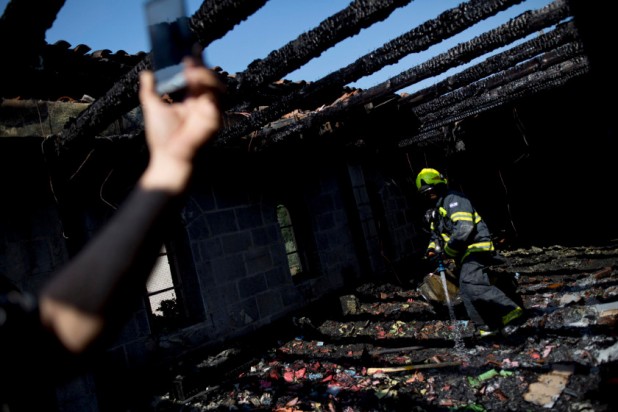 An Israeli fire fighter works in the heavily damaged Church of the Multiplication near the Sea of Galilee in Tabgha, Israel, Thursday, June 18, 2015. A fire broke out overnight at the Catholic church Thursday, in a possible arson attack by Jewish extremists. (AP Photo/Ariel Schalit)