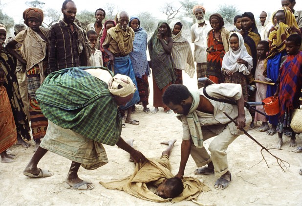 August 1992 - Berdale, Somalia - A starving child, so weak from hunger that he collapsed, is helped to his feet at Berdale.   Photo Credit: ANDREW HOLBROOKE/CORBIS