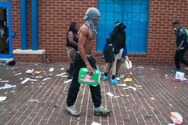 epa04723494 Looters walk with merchandise from a CVS during a protest for the death of Freddie Gray in Baltimore, Maryland, USA, 27 April 2015. Gray died of spinal cord injuries on 19 April while in police custody; the US Justice Department announced that they are launching their own investigation into the case.  EPA/NOAH SCIALOM