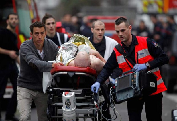 An injured person is evacuated outside the French satirical newspaper Charlie Hebdo's office, in Paris, Wednesday, Jan. 7, 2015. Police official says 11 dead in shooting at the French satirical newspaper. (AP Photo/Thibault Camus)