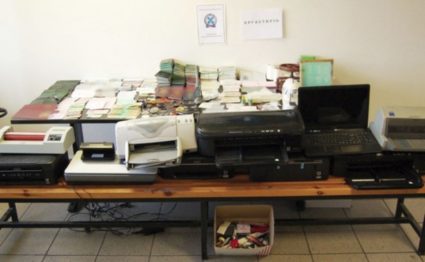 A police photo shows stacks of passports, documents, printers, and scanners, all seized from (legally resident) Pakistani-dominated gangs operating in Athens.