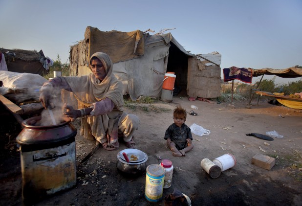 A Pakistani woman prepares food as her child plays on the ground outside their shanty on International Day for Eradication of Poverty at a slum in Islamabad, Pakistan on Monday, Oct. 17, 2011. Pakistan is facing high poverty rate, with a majority of people living below the poverty line. (AP Photo/Anjum Naveed)