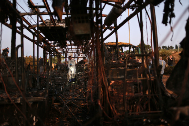 An Israeli police officer examines a burned bus in Jerusalem, Monday, April 18, 2016. A bus exploded in the heart of Jerusalem Monday wounding at least 15 people who appeared to have been in an adjacent bus that was also damaged. The explosion raised fears of a return to the Palestinian suicide attacks that ravaged Israeli cities a decade ago. (AP Photo/Oded Balilty)