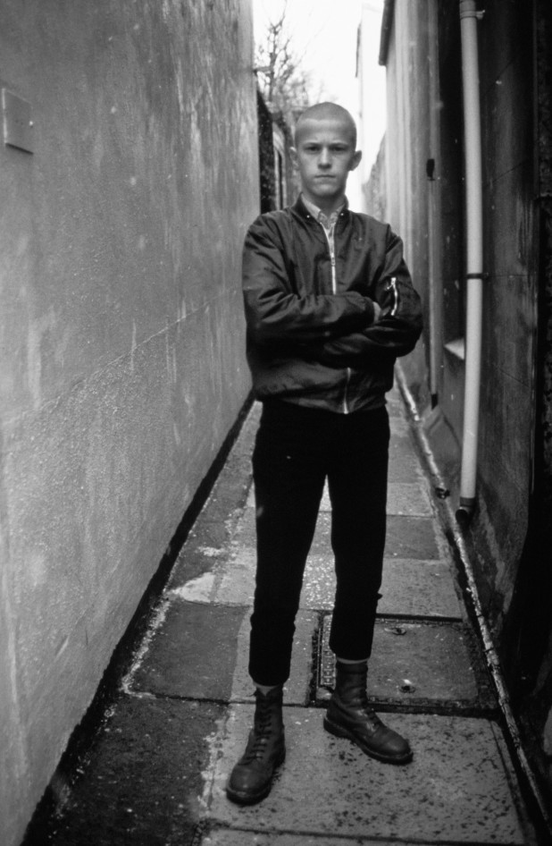 Kenny, a young skinhead standing in an alley way wearing cherry red Dr Marten boots, Brighton, UK 12th Feb 1983