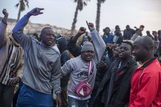 Would-be immigrants of the Centre for Temporary Stay of Immigrants (CETI) cheer other ones who want to cross the fence near Beni Enza, into the north African Spanish enclave of Melilla on March 28, 2014. Several hundreds people launched a dawn assault today to cross into the Spanish city, which lies on the northern tip of Morocco, and dozen made it across.      AFP PHOTO/ JOSE COLONJOSE COLON/AFP/Getty Images