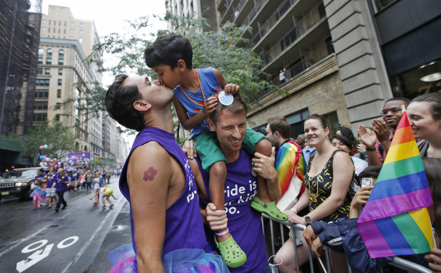 Rafael Gondim, left, kisses his five year-old son Gabriel King, as his husband Courtney King holds the child while the trio marches down Fifth Avenue during the Heritage Pride March in New York, Sunday, June 28, 2015. A large turnout was expected for gay pride parades across the U.S. following the landmark Supreme Court ruling that said gay couples can marry anywhere in the country. (AP Photo/Kathy Willens)