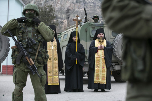 Orthodox clergymen pray next to armed servicemen near Russian army vehicles outside a Ukrainian border guard post in Ukraine's Crimean region March 1. Catholic leaders in Crimea say Ukraine has the right to determine its own future, and they urge prayers for peace. (CNS photo/Baz Ratner, Reuters) (March 5, 2014) See UKRAINE-CRIMEA March 5, 2014.