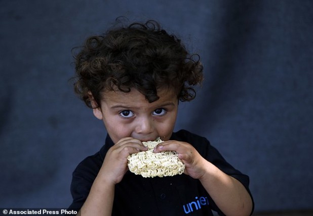 A migrant child eats at a makeshift camp for migrants in Horgos, Serbia, meters away from Serbia's border with Hungary, Thursday, Aug. 25, 2016. Officials say Hungary's police could join the Serbian troops patrolling the Balkan country's border with Macedonia or Bulgaria to help curb the influx of migrants trying to reach the European Union. (AP Photo/Darko Vojinovic)