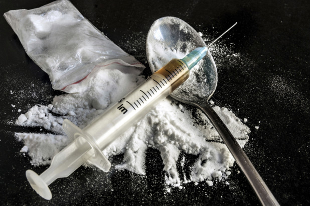 Drug syringe and cooked heroin on spoon