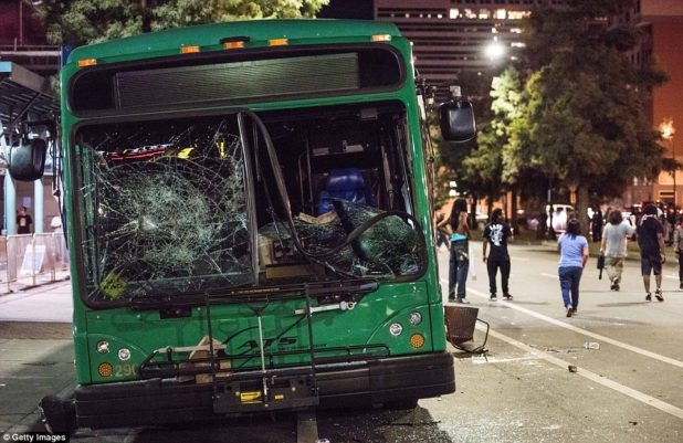 38ae9e0b00000578-3802230-demonstrators_walk_near_a_damaged_bus_the_north_carolina_governo-m-11_1474555793085