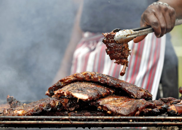 Pit master Eric Smith of Atlanta BBQ Masters flips some pork ribs at the start of Jazz & Rib Fest on Spring and Long Street along downtown Columbus on July 18, 2014. Smith a former Columbus resident has been bring Atlanta BBQ Masters up to the Jazz & Rib Fest since 2007. (Dispatch photo by Kyle Robertson)