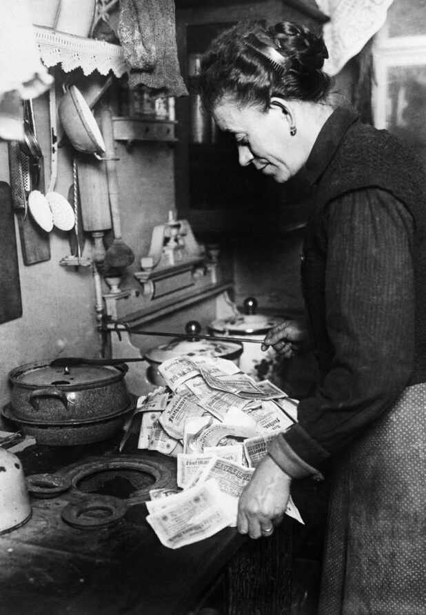 A woman uses banknotes to light her stove. 1923.